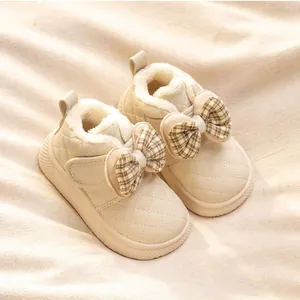 Close-up of cream baby winter boots featuring a decorative plaid bow and soft plush lining