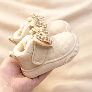 Close-up of baby girl winter boots with a plush fleece lining and a checkered bow detail