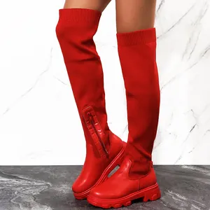 Détail montrant des bottes cuissardes rouges en maille avec de larges semelles à plateforme.