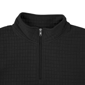Primer plano de sudadera acolchada negra con detalle de media cremallera plateada.