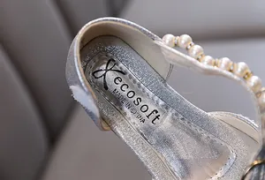 Nahaufnahme der silbernen Glitzertextur und des Perlendetails an Mädchenschuhen