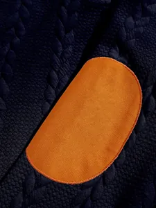 Close-up of jacquard fabric texture and orange oval elbow patch on a men's sweatshirt