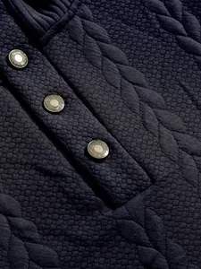 Macro view of navy heavy jacquard sweatshirt showing textured quilted fabric and metal buttons.