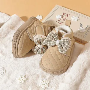 Close-up of beige quilted baby boots with warm plush lining and plaid bow detail