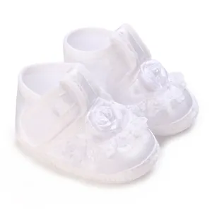 Detailed view of white soft sole baby christening shoes with lace and rose decor.