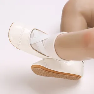 Gros plan de chaussures de princesse pour bébé en cuir verni blanc avec semelles souples.