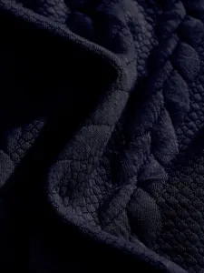 Close-up macro detail of heavy jacquard fabric texture on men's Henley shirt.