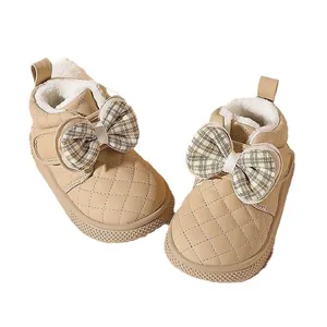 Warm beige baby girl winter boots with quilted pattern and large plaid bow detail.
