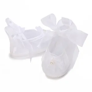 Close-up of white baby girl baptism shoes with organza bows and pearl detail