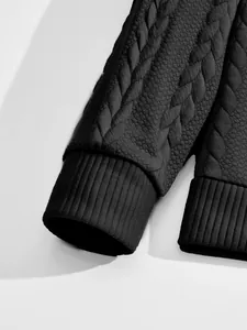 Close-up macro detail of premium black jacquard fabric and ribbed cuff on a men's sweatshirt.