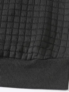 Detailaufnahme eines schwarzen Herren-Sweatshirts mit quadratischer Gitterstruktur und Rippsaum.