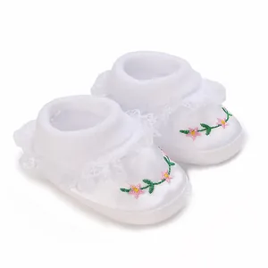 Close-up detail of white baby christening shoes with floral embroidery and lace trim