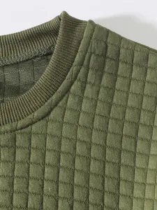 Nahaufnahme eines olivgrünen Herren-Sweatshirts mit gesteppter Textur und Rippstrickbund