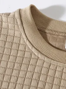 Detailaufnahme eines beigen Herren-Stepp-Sweatshirts mit Rippbündchen und Gitterstruktur.