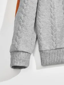 Close-up detail of grey jacquard quilted sweatshirt cuff and ribbed hem with orange stripe