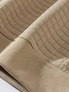 Nahaufnahme des beigen karierten Stoffes und der Rippstruktur dieses lässigen Sweatshirts