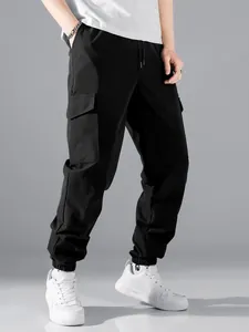 Detailed view of men's black cargo jogger pants with large functional side flap pockets