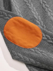 Close-up of premium heavy jacquard fabric and orange elbow patch on men's sweatshirt