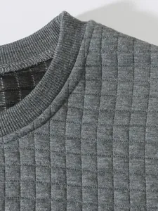 Nahaufnahme des gesteppten Karomusters und des gerippten Rundhalsausschnitts am Sweatshirt