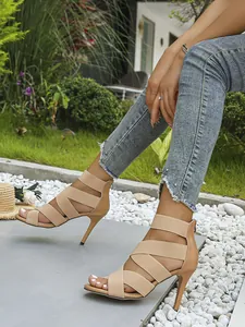 Outdoor detail of nude high-heel sandals with elastic straps and back zipper on model