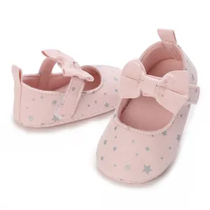 Vista detallada de zapatos rosa para bebé con estrellas plateadas y un lazo elegante