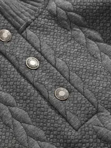 Close-up of quilted jacquard fabric and metal snap buttons on a grey men's sweatshirt