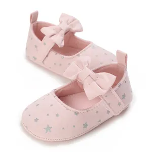 Primer plano de zapatos Mary Jane rosas para bebé con estrellas plateadas y lazo