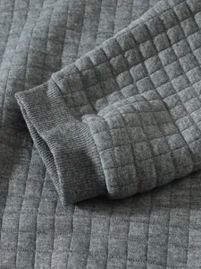 Detailansicht eines grauen gesteppten Herren-Sweatshirts mit Rippbündchen und Karomuster