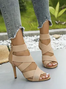 Close-up of stylish beige high heel sandals with elastic crisscross straps and zipper