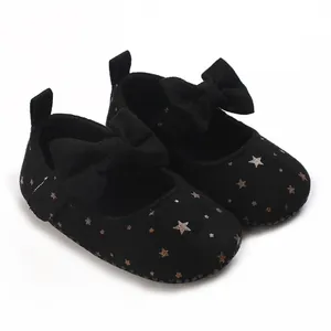 Detalle de zapatos negros para bebé con patrón de estrellas doradas y un lazo grande