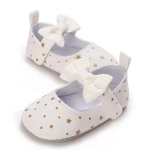 Detalle de zapatos para bebé blancos con estrellas doradas y un elegante lazo decorativo
