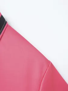 Hochwertige Detailaufnahme der rosa Stoffstruktur und der schwarzen Kragennaht dieses Poloshirts