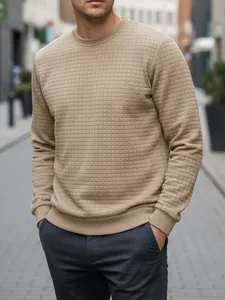 Nahaufnahme eines khakifarbenen Herren-Sweatshirts mit Gittermuster in Stadtumgebung