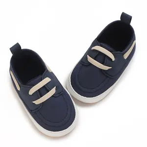 Vista dall'alto di scarpine in tela blu navy per neonato con lacci beige e suola.