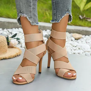 Elegant beige high heel sandals featuring elastic criss-cross straps and a secure back zipper