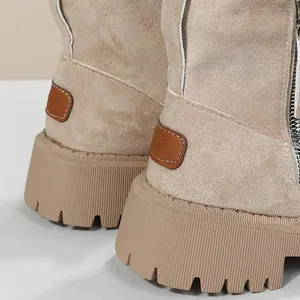 Gros plan de bottes de neige en daim beige avec semelles crantées et fermeture éclair