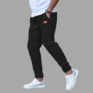Stylish men's solid black joggers featuring a drawstring waist and decorative pocket patch