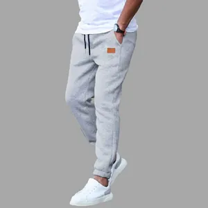 Close-up view of men's grey casual joggers featuring a stylish brown leather patch detail.