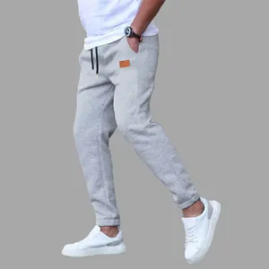 Men's casual grey joggers featuring a drawstring waist and stylish patch detail.