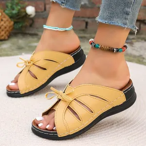 Detailansicht modischer gelber Keilsandalen mit Schleife und elegantem Lochmuster-Design