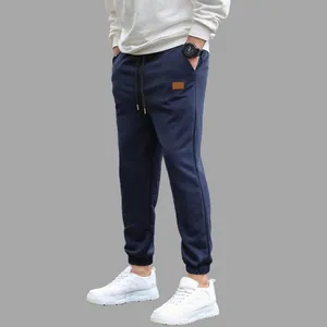 Men's navy blue drawstring joggers with elasticated cuffs and decorative tan patch detail