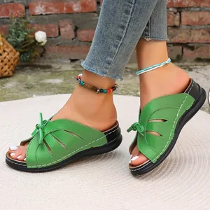 Detail grüner Peeptoe-Sandalen mit Cutout-Design und Schleifenakzent auf Keilsohle
