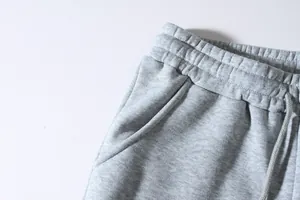 Close-up of grey men's casual sweatpants featuring an elastic waistband and drawstring detail