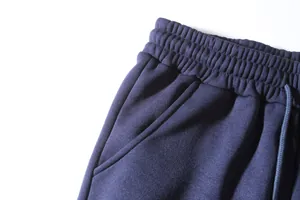 Close-up detail of navy blue joggers showing elastic waistband and side pocket texture