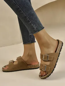 Detail view of retro brown suede double-buckle sandals on feet for summer beach leisure