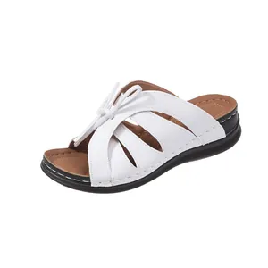 Elegante weiße Damen-Pantoletten mit Keilabsatz, Cut-out-Design und dekorativer Schleife.