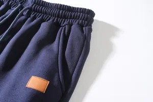 Close-up of navy blue cargo pants featuring elastic waistband and leather patch detail.