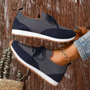 Vista dettagliata delle scarpe da ginnastica in maglia blu scuro e grigio con suole bianche da donna.