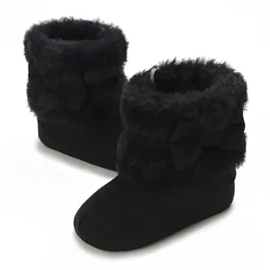 Close-up detail of black infant warm boots featuring soft faux fur and bow decorations.