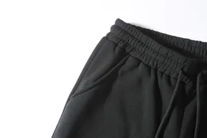 Close-up of black men's sports pants with elastic drawstring waistband and side pocket.